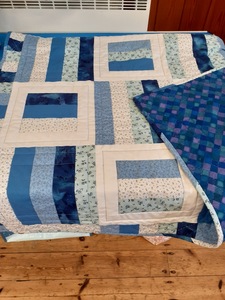 The colourful lap quilt has been made from her stash of material by Jenny C. The range of blue has been combined to eye-catching effect.